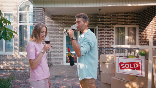 homme tenant bouteille de vin tout en cliquetis verres avec femme près de nouvelle maison - Séquence, vidéo
