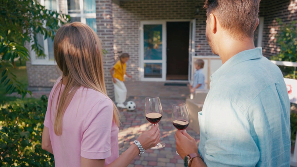 selectieve focus van paar met glazen wijn in de buurt van kinderen en nieuw huis - Video