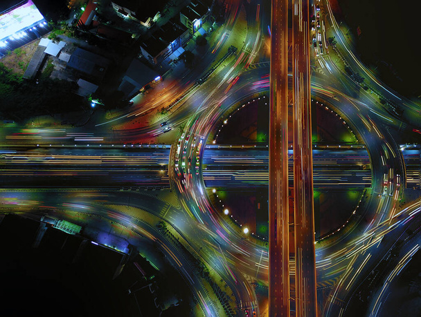 Αεροφωτογραφία του κύκλου οδικής κυκλοφορίας σε κυκλικό κόμβο και αυτοκινητόδρομο τη νύχτα, Expressway, Σύγχρονες μεταφορές, Πολυεπίπεδο αυτοκινητόδρομο διασταύρωση, Σημαντική υποδομή των μεταφορών στην Ταϊλάνδη, Top view. - Φωτογραφία, εικόνα