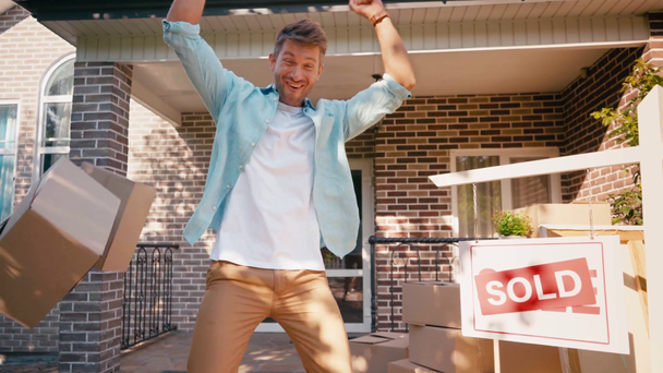 homem apontando com a mão para a placa vendida, jogando caixas e pulando perto de casa - Filmagem, Vídeo