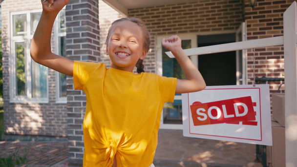 alegre niño mostrando llaves y bailando cerca de nueva casa - Imágenes, Vídeo