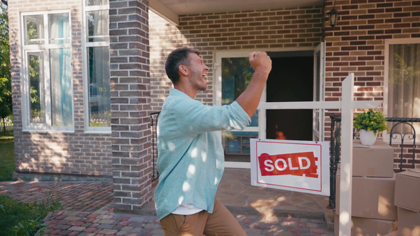 чоловік ловить ключі і вказує рукою на продану дошку біля будинку
 - Кадри, відео