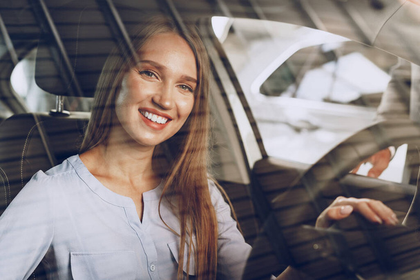 Attractive young woman sitting in new car in showroom - Fotografie, Obrázek