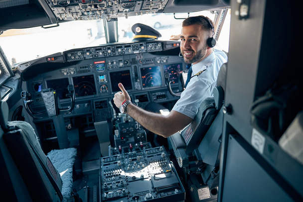 Bonito homem de uniforme mostrando como na cabine de aeronaves - Foto, Imagem