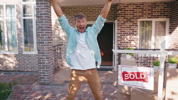 vzrušený muž ukazuje rukama na nový dům, křičí a skáče ven - Záběry, video