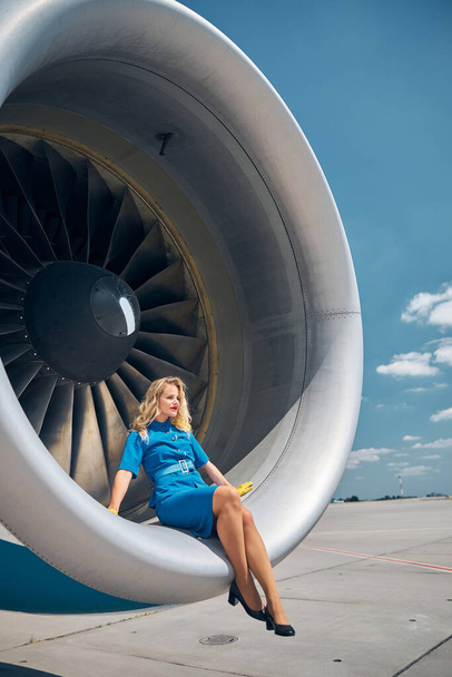 Beautiful flight attendant sitting in plane engine - Photo, Image