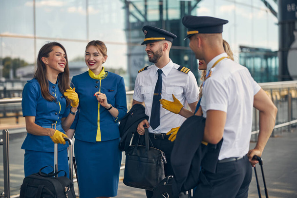 Веселые работники авиакомпании разговаривают на улице - Фото, изображение