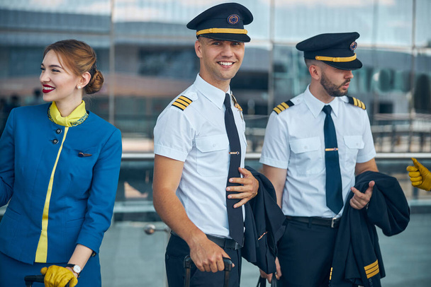 Χαρούμενοι πιλότοι και αεροσυνοδός που στέκονται στο δρόμο - Φωτογραφία, εικόνα