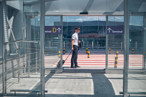 Handsome male pilot standing outside airport terminal - Photo, Image