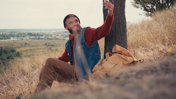 Podróżnik pokazując gest powitania i kciuk w górę podczas korzystania z telefonu na wzgórzu - Materiał filmowy, wideo