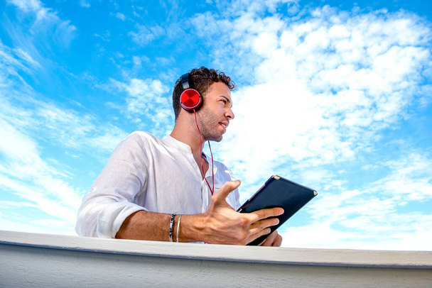 bel homme caucasien qui écoute de la musique sur la plage. freelance et télétravail. étudiant sur la rive méditerranéenne - Photo, image