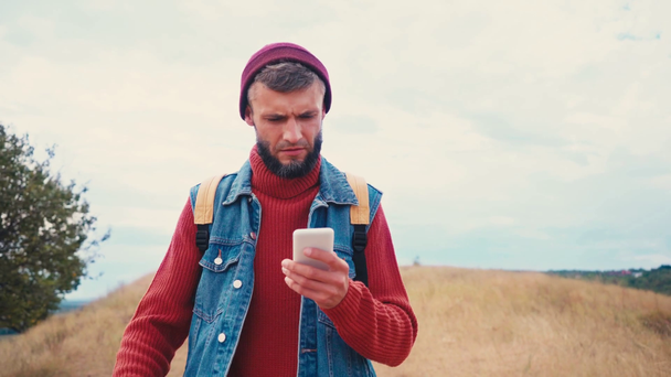 Voyageur tenant son téléphone portable, marchant et regardant autour de lui - Séquence, vidéo