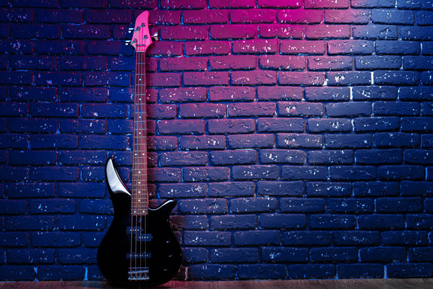 Electric guitar in neon light against dark walll - Photo, Image