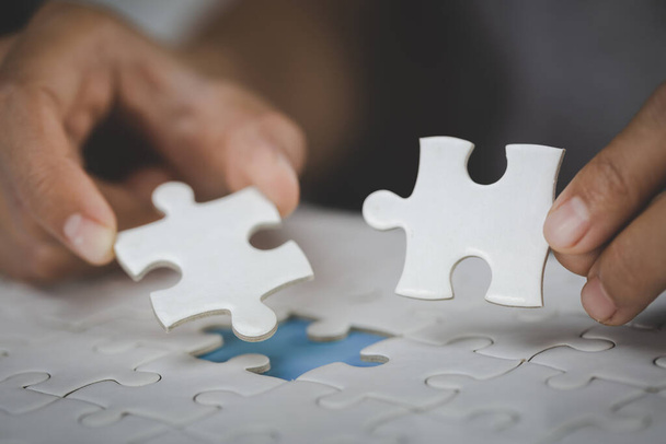 Twee handen van zakenman om puzzelstukjes met elkaar te verbinden. symbool van associatie en verbinding. bedrijfsstrategie. - Foto, afbeelding