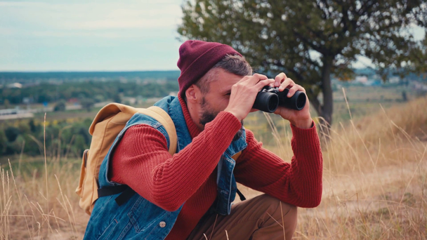 Traveler sitting down and looking through binoculars outside - Footage, Video