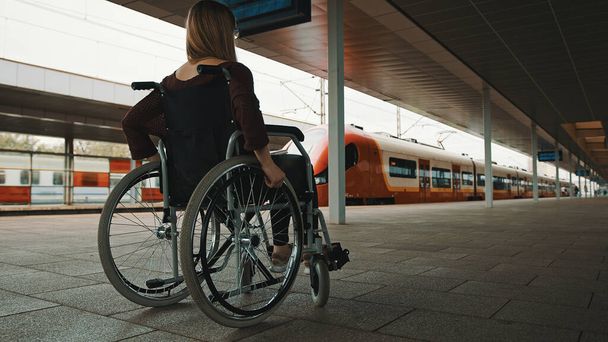 Νεαρή με ειδικές ανάγκες που περιμένει το τρένο στην αναπηρική καρέκλα - Φωτογραφία, εικόνα