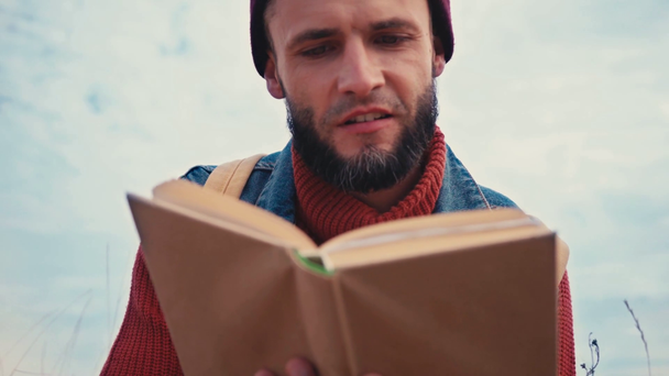 Niski kąt widzenia człowieka czytania książki na zewnątrz - Materiał filmowy, wideo