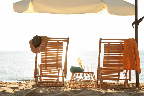 Wooden deck chairs, outdoor umbrella and beach accessories near sea. Summer vacation - Photo, Image