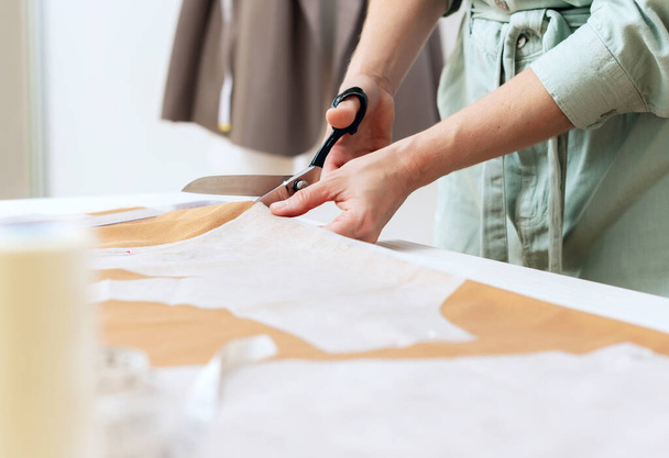 pattern, scissors, tape measure, and a sewing machine. Workplace of seamstress. Dressmaker cuts dress detail on the sketch lines. - Photo, Image