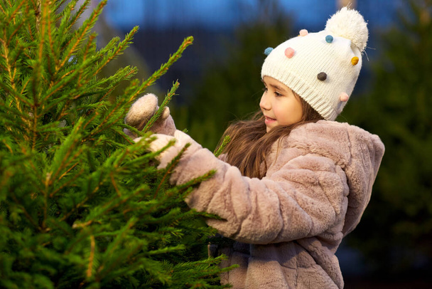 little girl choosing christmas tree at market - Foto, Imagen