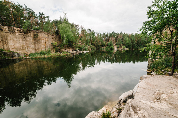 Landscape of an old flooded industrial granite quarry filled with water. Lake on the background of rocks and fir trees. Canyon The nature of the autumn. Place for text and design. - Foto, Imagen