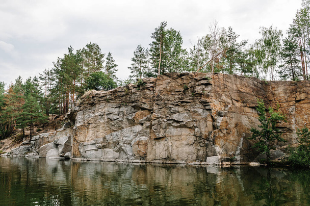 Lake on the background of rocks and fir trees. Canyon. The nature of autumn. Place for text and design. Landscape of an old flooded industrial granite quarry filled with water. - 写真・画像