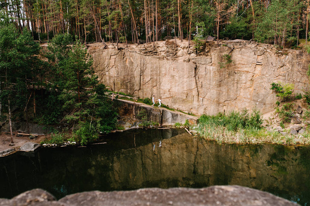 Landscape of an old flooded industrial granite quarry filled with water. reflected people in lake on the background of rocks and fir trees. Canyon. The nature of autumn. Place for text and design. - Foto, Bild