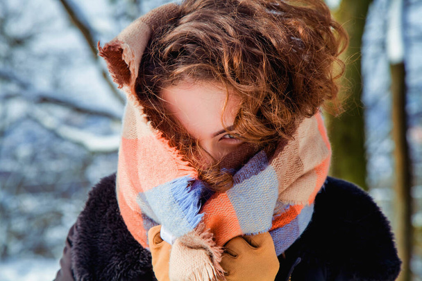 Schöne Frau mit lockigem Haar im Winterwald und genießt den ersten Schnee. Selektiver Fokus auf die Augen. - Foto, Bild