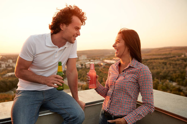 Cheerful couple drinking beer on rooftop - Photo, image