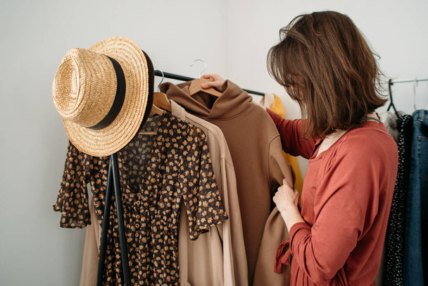 wardrobe, young woman chooses and hangs clothes - Фото, изображение