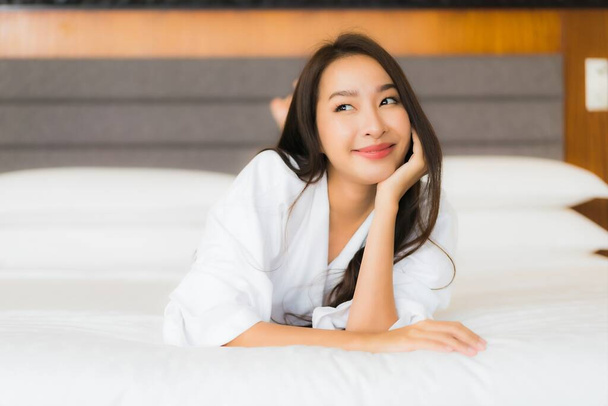 Πορτρέτο όμορφη νεαρή Ασιάτισσα γυναίκα χαλαρώστε χαμόγελο στο κρεβάτι στο εσωτερικό υπνοδωμάτιο - Φωτογραφία, εικόνα