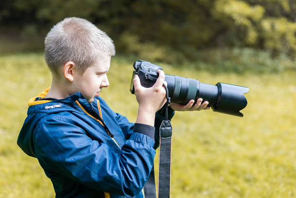 Νεαρός καυκάσιος που φωτογραφίζεται με την κάμερα του DSLR. Φύση περιβάλλοντος.  - Φωτογραφία, εικόνα