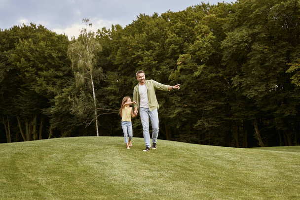 Apával töltöm az időt. Fiatal apa és aranyos kislánya sétálnak a parkban egy meleg nyári napon. - Fotó, kép