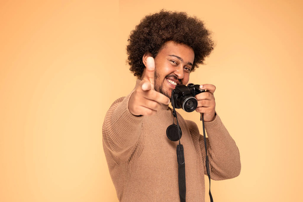 Cheerful afro guy taking photos with a camera. - Фото, изображение