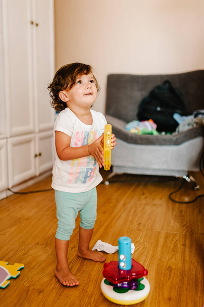 Πορτρέτο ενός μικρού παιδιού, κορίτσι, αξιολάτρευτο μωρό παίζει πυραμίδα χρώμα στο πάτωμα σε εσωτερικούς χώρους, μικρό παιδί παίζουν, το παιχνίδι σε ένα δωμάτιο στο σπίτι ή νηπιαγωγείο. - Φωτογραφία, εικόνα