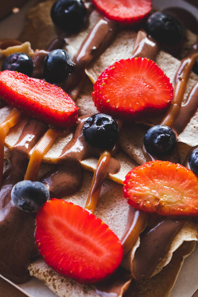 A vertical shot of delicious crepes with berries and caramel - Фото, изображение