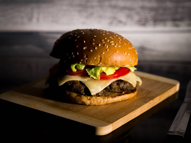 A closeup of hamburger served on a wooden surface - Foto, Imagem