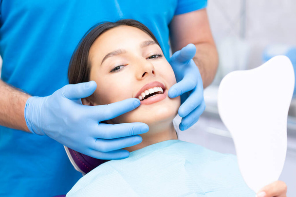 Tandarts en patiënt in het tandartspraktijk. Vrouw met tanden onderzocht door tandartsen - Foto, afbeelding