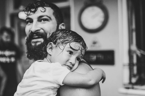 Dad holds his daughter, wet girl on her hands, during the walk got under the rain. Black and white photo. - Φωτογραφία, εικόνα