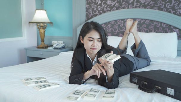 Negocios ricos Mujer tailandesa asiática contando dinero para ahorrar billetes en cuenta financiera y concepto de inversión en la cama en el dormitorio en el hotel. - Foto, Imagen