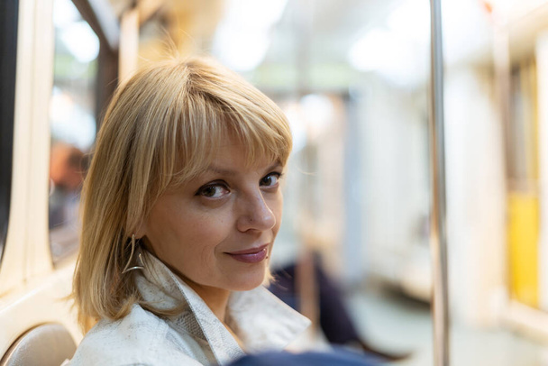 Portrait of beautiful adult woman sitting in the subway and looking at camera. - 写真・画像