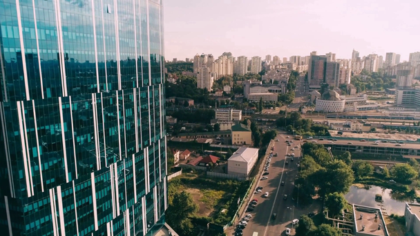 Вид с воздуха на фасад небоскреба, автомобильную дорогу и здания  - Кадры, видео