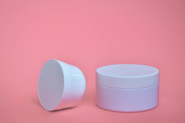 Kulatá, bílá, plastová kosmetická nádoba, dispozice izolovaná na růžovém pozadí. - Fotografie, Obrázek
