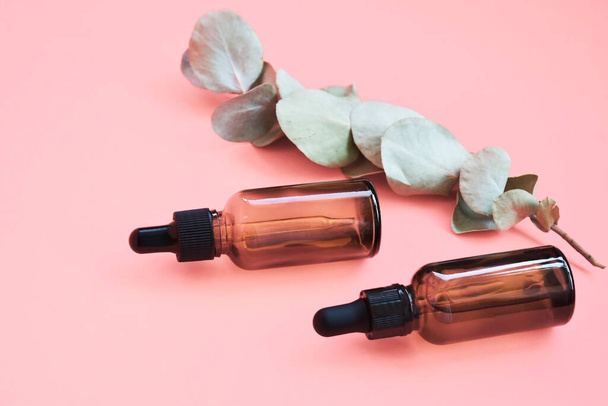Natural serum, skin care, essential oils. Cosmetic brown glass bottle with dropper on a pink background. Layout of cosmetics branding. Top view. - Fotoğraf, Görsel