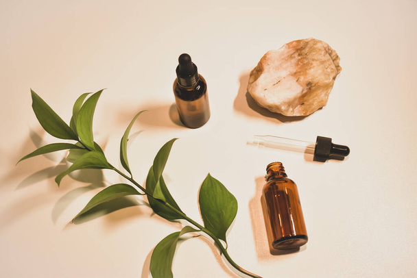 Luonnollinen kosmeettisia öljyjä luonnon beige tausta sisustus niiden kivet ja kasvien lehtiä. Eco kosmetiikka ja lääke kasvojen ja kehon. - Valokuva, kuva