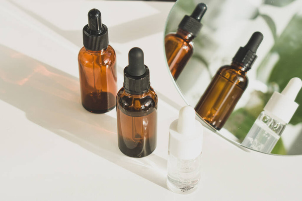 Spa cosmetics in brown glass bottles on a white table. Beauty blogger, salon therapy, branding layout, minimalism concept. Top view, copy space - Foto, afbeelding