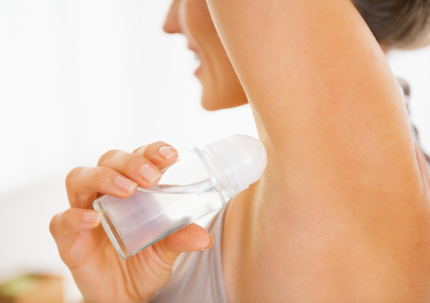 Closeup on young woman applying deodorant on underarm - Photo, image