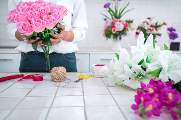 Arranging artificial flowers decoration at home, Young woman florist work making organizing diy artificial flower, craft and hand made concept. - Foto, Imagen