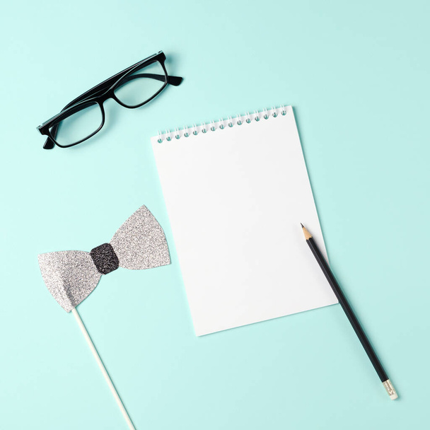 Open notebook with pencil, glasses and bow tie on a blue background. Copy space, top view flat lay overhead. Father's day or men's day concept - Фото, изображение