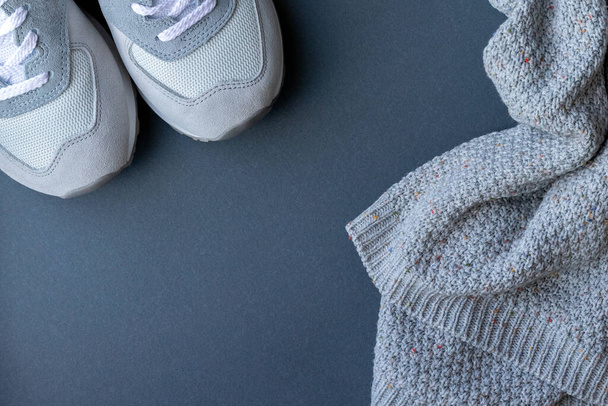 Light gray suede and mesh walking shoes, sneakers and a warm knitted sweater on a gray paper background - Zdjęcie, obraz
